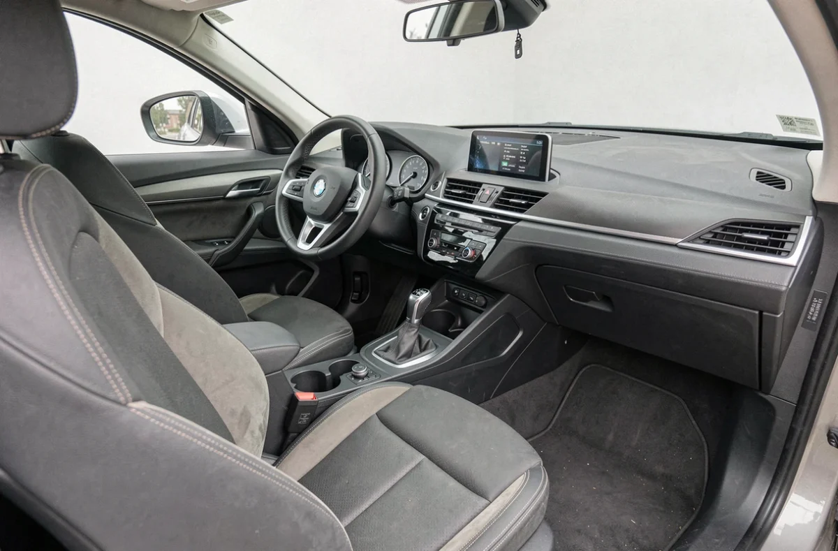 Intérieur usagé d'un BMW X1 F48 à fort kilométrage montrant les signes normaux d'utilisation sur les sièges et le tableau de bord