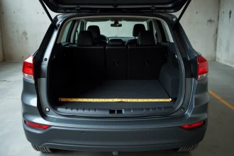 Coffre ouvert d'un SUV compact Peugeot vue arrière trois quarts avec mètre ruban mesurant le volume utile réel