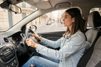 Élève conductrice concentrée au volant lors d'une leçon de conduite dans une auto-école