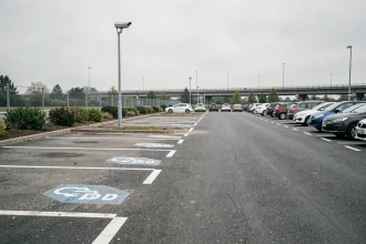 Vue large du parking de covoiturage Vinci Autoroutes à La Chapelle-Saint-Mesmin avec caméra de surveillance sur poteau métallique et places marquées au sol