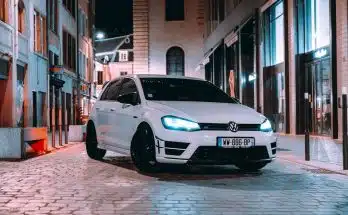 a white car parked on a brick road between buildings