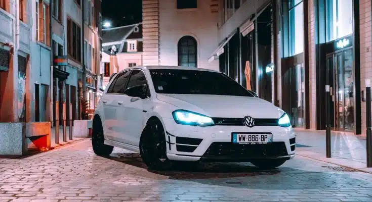 a white car parked on a brick road between buildings